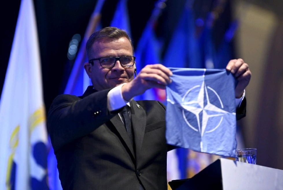 Kokoomuksen puheenjohtaja Petteri Orpo nostaa Nato-lipun linjapuheessaan kokoomuksen puoluekokouksessa Kalajoella 10. kesäkuuta 2022.