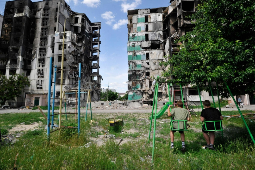 Lapset keinuivat tiistaina tuhottujen kerrostalojen edustalla Borodjankassa lähellä Ukrainan pääkaupunkia Kiovaa. LEHTIKUVA / AFP