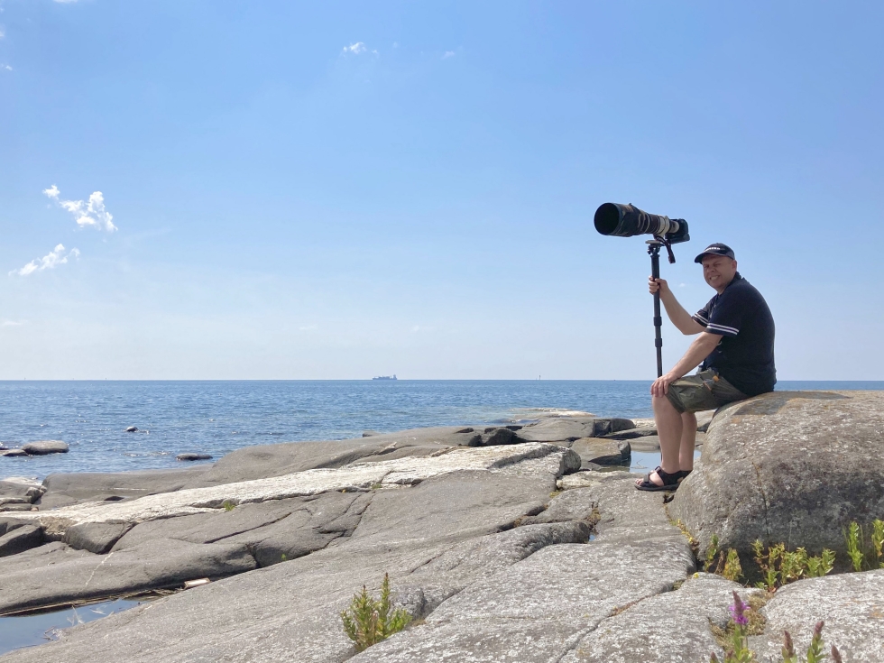 Rami Hiipakka paistattelemassa päivää kameransa kanssa Kylmäpihlajan majakan luona. Se sijaitsee kauimmalla saarella Rauman edustan saaristossa. 