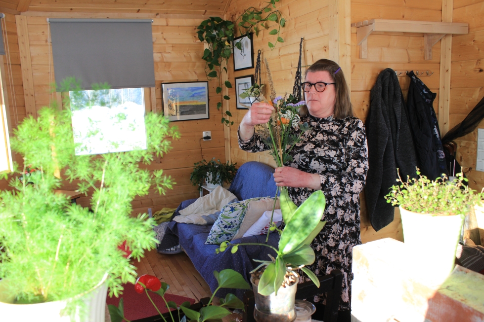 Raisa Nurminen teki kukkakimppua mökissä, joka rakennettiin hänelle työtilaksi perheen kotitilan Kaisaniemen pihaan Lapväärttiin. ‑ Mökki on valoisa ja täällä viherkasvit ja kukat viihtyvät.