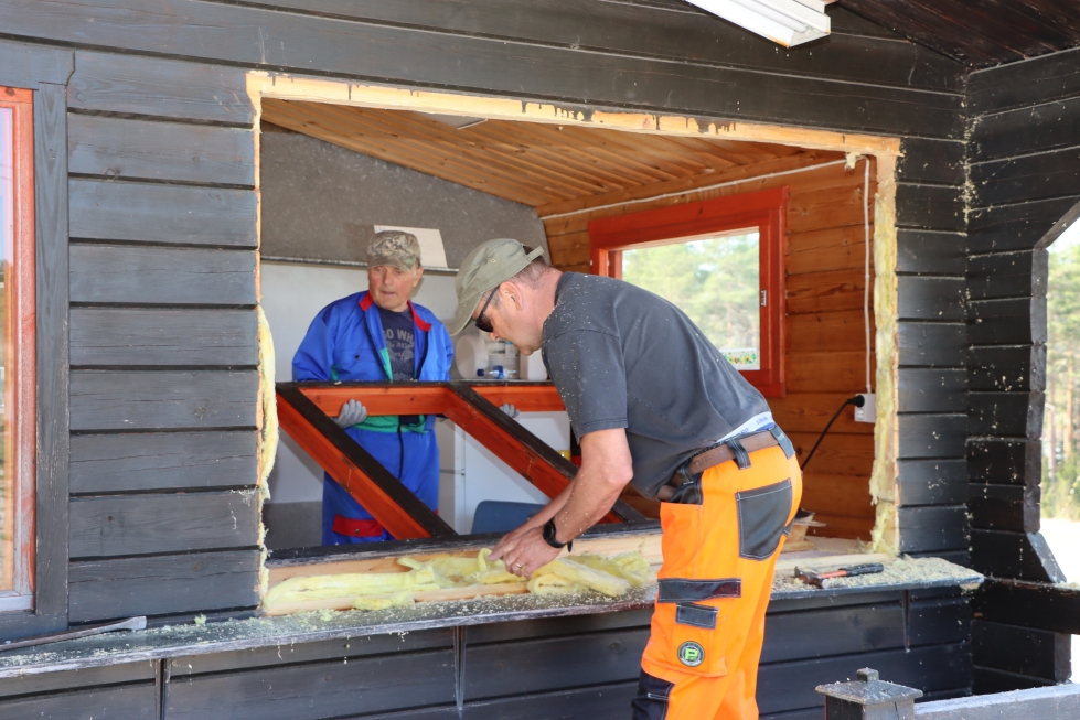 Heikki Ikola ja Esko Pietilä vaihtavat huoltorakennukseen avattavia ikkunoita. Vanha leikattiin irti moottorisahalla. Naiset pitävät rakennuksessa kisojen aikana kioskia ja myyvät makkaraa. 