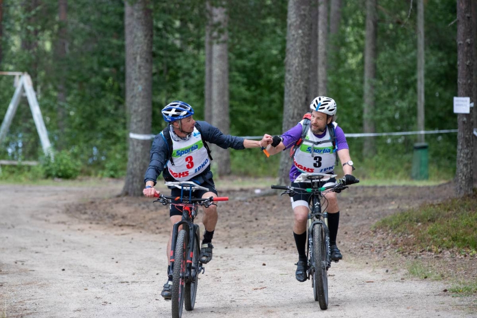Olli-Pekka Holttinen (vas.) ja Pekka Sorjonen saapumassa maaliin. Karelian Seikkailu-urheilijoiden pitkäaikaiset jäsenet suuntasivat syömään heti 170 kilometrin urakan jälkeen.