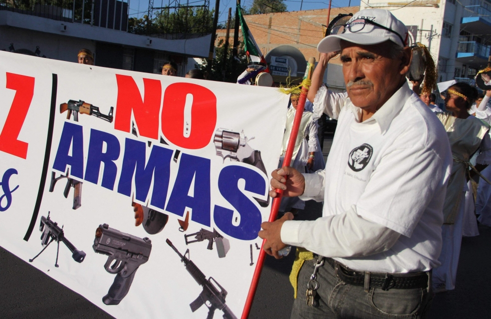 "Ei aseille", lukee väkivaltaa vastustavan mielenosoitusmarssin osallistujan julisteessa Meksikon Chihuahuan osavaltiossa. Arkistokuva kesäkuulta 2018. LEHTIKUVA / AFP