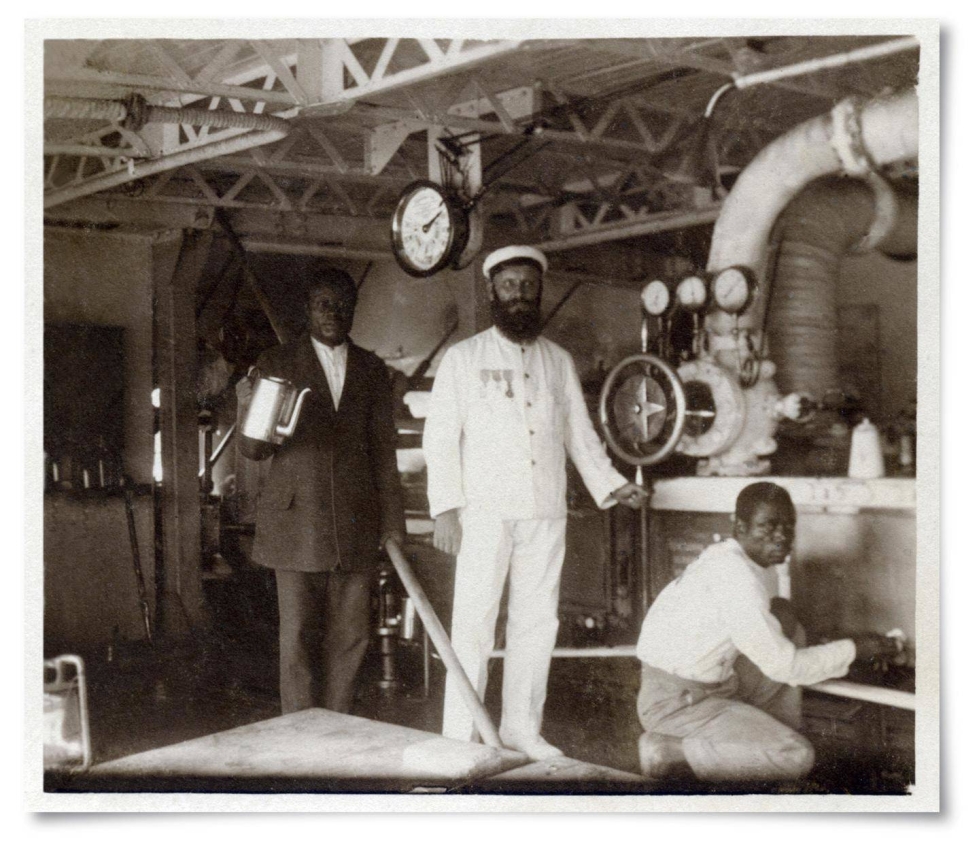 Akseli Leppänen konehuoneessa kongolaisten apulaistensa kanssa. Paikallisista työntekijöistä vasemmalla Pai-Pai ja oikealla Mamgamba. Kuva on poikkeuksellinen, koska valokuvissa esiintyviä mustia työntekijöitä nimettiin harvoin.