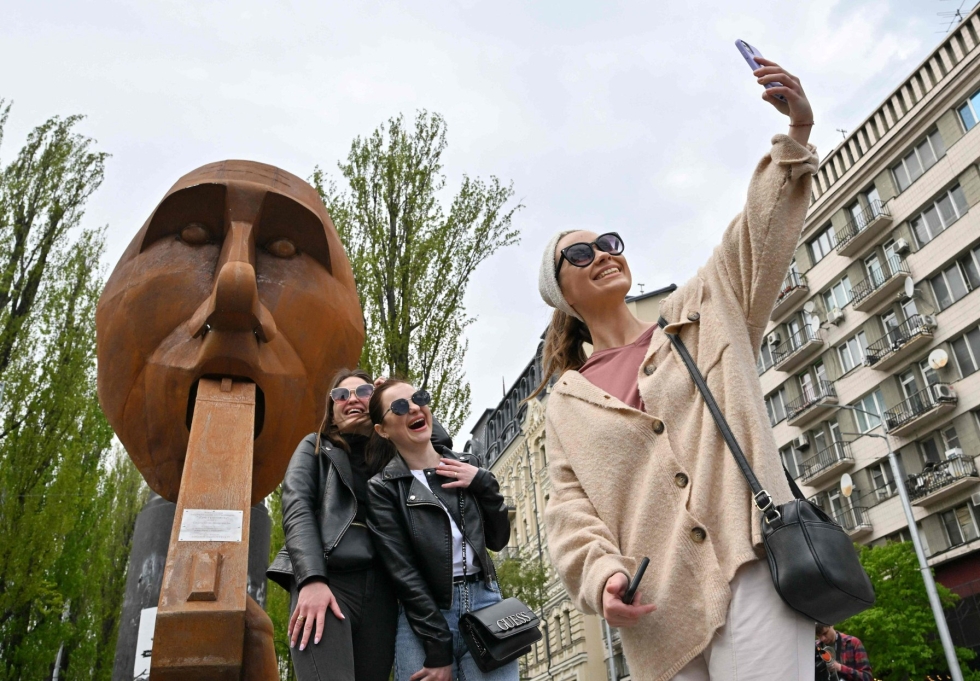Naiset ottivat lauantaina kuvia Venäjän presidenttiä Vladimir Putinia kuvaavan muistomerkin edessä Kiovassa. Ukrainalaisen kuvanveistäjän patsaan nimi on "Ammu itsesi". Lehtikuva/AFP