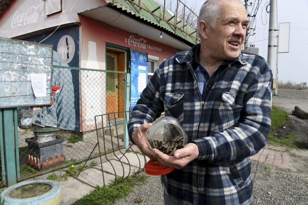 Kauppaa pitävä Volodymyr Koryk on siivonnut ämpäreittäin luodin hylsyjä talonsa pihamaalta Skybynin kylässä Ukrainassa. LEHTIKUVA / JUSSI NUKAR