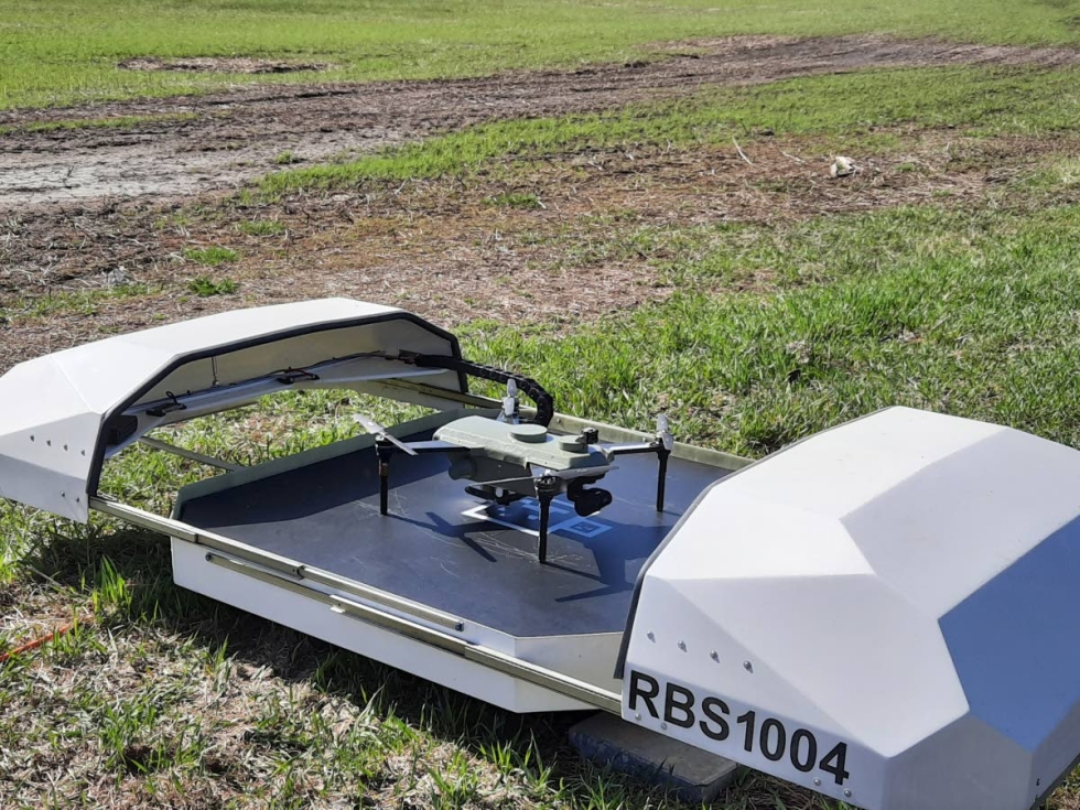 Drone on lähdössä latausasemalta. Se lentää ennalta suunniteltua reittiä aivan itsenäisesti. Droonit ovat jo osoittaneet toimivuutensa. Takana oleva pelto on säästynyt hanhituhoilta, ja vilja saa kasvaa rauhassa.