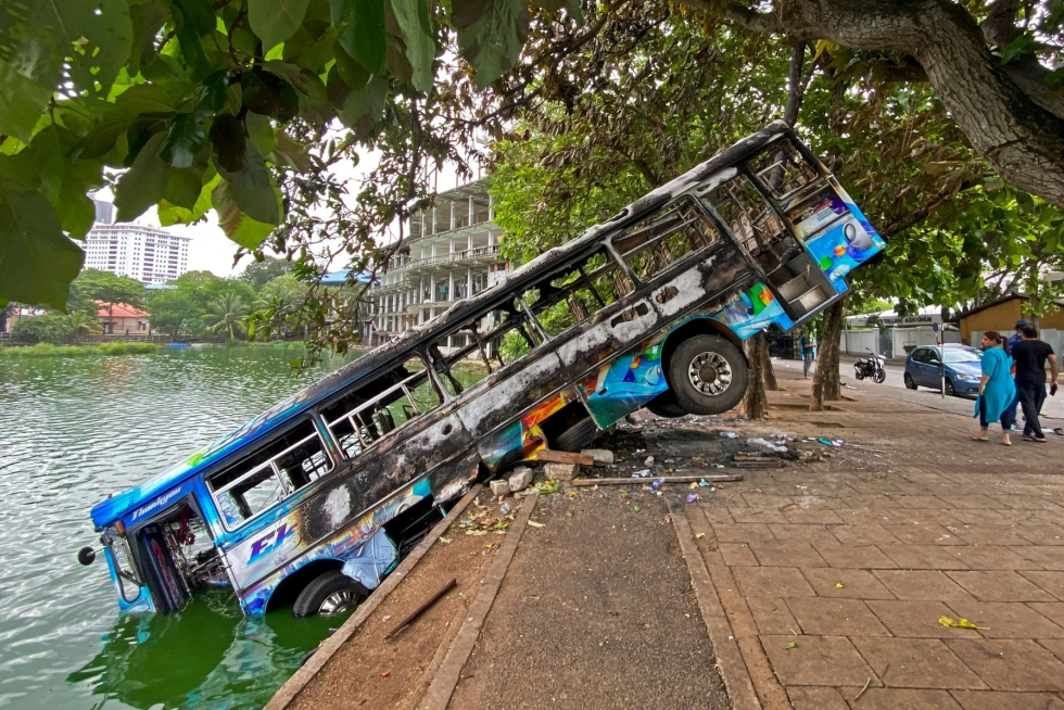 Mielenosoittajien tuhoama linja-auto lähellä ex-pääministeri Mahinda Rajapaksan virka-asuntoa tiistaina. LEHTIKUVA