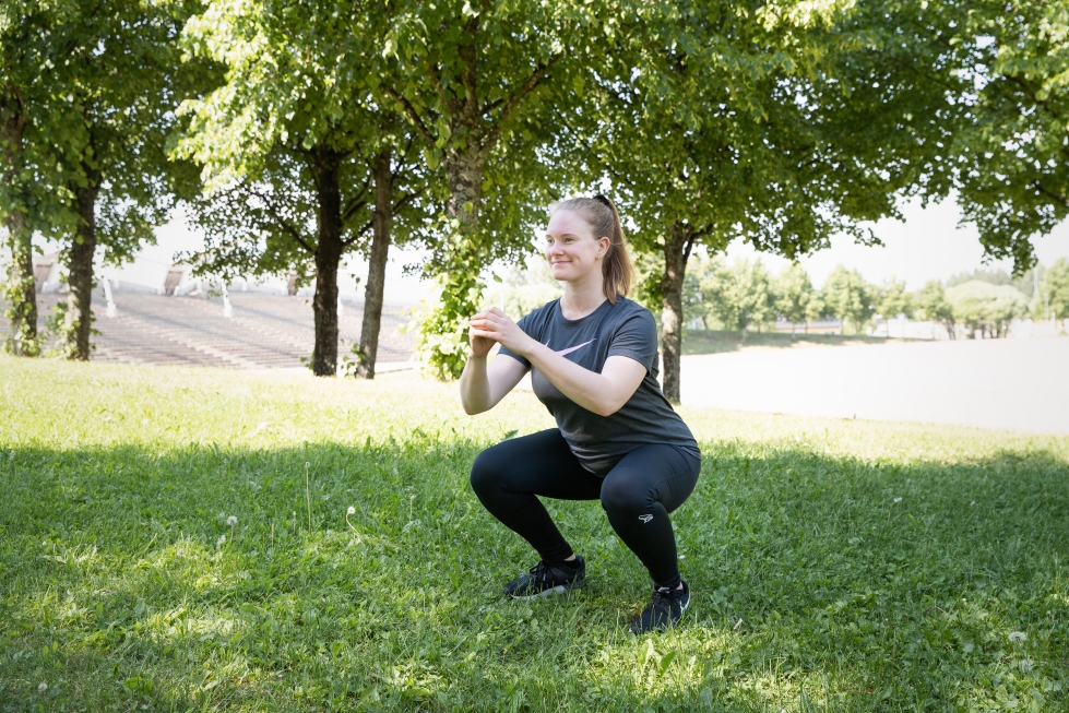 Itä-Suomen liikuntaopiston liikunnanohjaaja Jenna Hiltunen näyttää, kuinka teet liikkeet oikein. Tässä tehdään jalkakyykkyä polven nostolla.