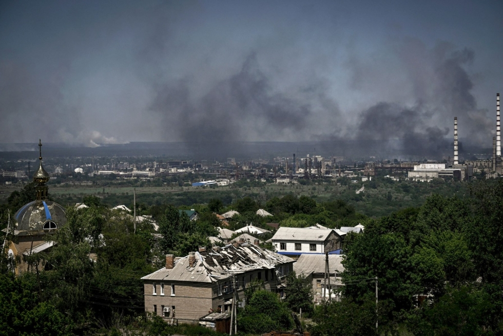 Etualalla vaurioitunut rakennus Ukrainan Lysytshanskissa. Mustaa savua nousee läheisestä Sjevjerodonetskin kaupungista Venäjän ja Ukrainan taistelualueella Itä-Ukrainan Donbassissa 9. kesäkuuta. Lehtikuva/AFP