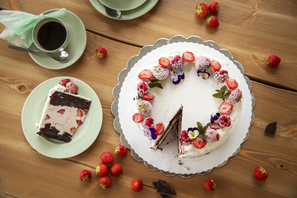 Suklaakakkupohjien välissä on reilu kerros itse tehtyä mansikkajäätelöä. Jäätelökakun voi koristella täytekakun tapaan kermalla, marjoilla ja syötävillä kukilla.
