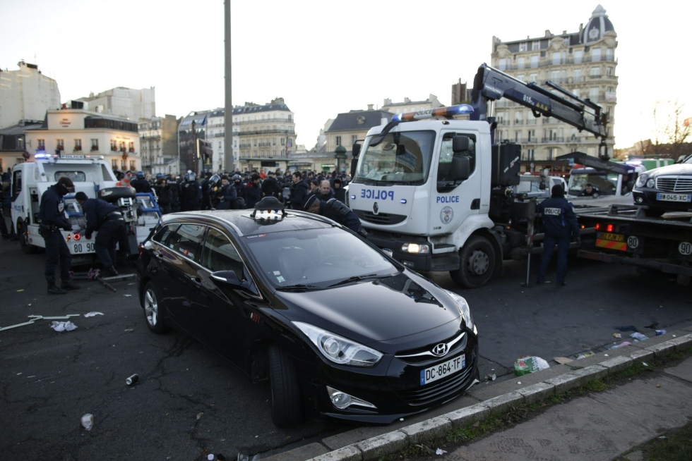 Poliisit siirsivät pois takseja Pariisissa tammikuussa 2016, kun taksikuskit osoittivat mieltään Uberia vastaan. LEHTIKUVA/AFP