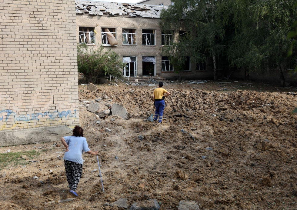 Asukkaita vaurioituneen koulurakennuksen ympäristössä ilmahyökkäyksen jäljiltä Mykolaivkan kaupungissa Ukrainan Donetskissa. 26. elokuuta. LEHTIKUVA / AFP