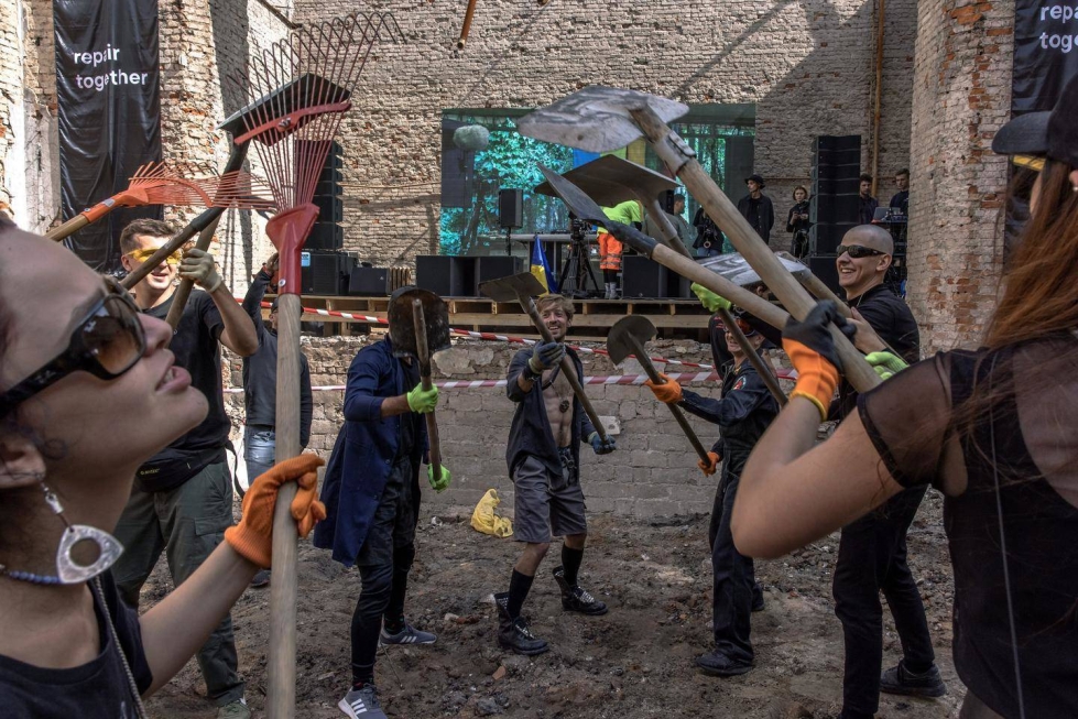 Vapaaehtoiset tanssivat siivotessaan venäläisten pommituksen jälkiä Ivanivkan kylän kulttuuritalolla lauantaina.