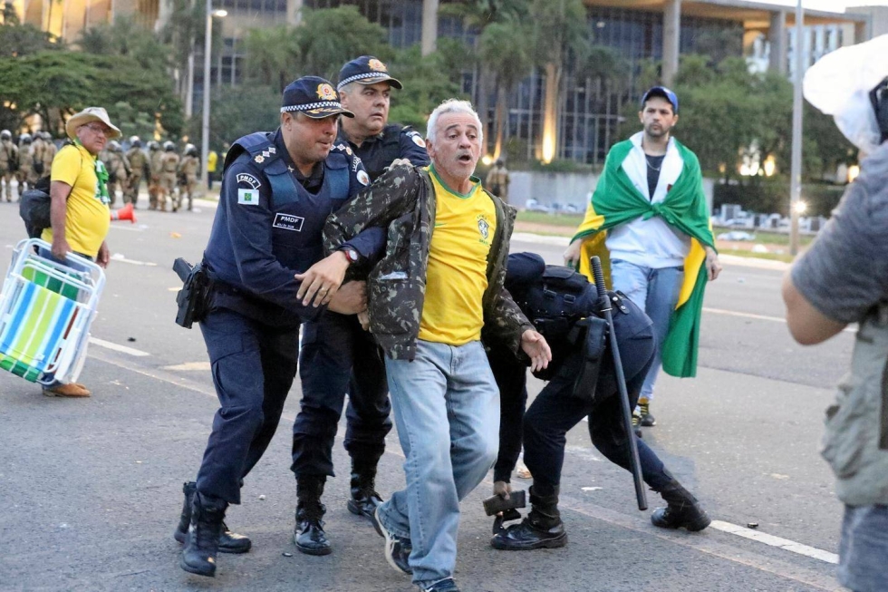 Ex-presidentti Jair Bolsonaron tukijaa vietiin pois hallintorakennusten tuntumasta Brasilian pääkaupungissa Brasiliassa. Viranomaisten tiedot pidätettyjen määrästä vaihtelivat 200:n ja 400:n välillä.