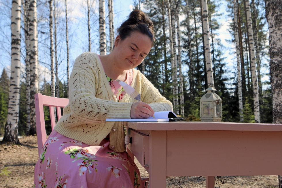 Anna Pölkki haaveilee, lukee kirjoja ja kirjoittaa metsän reunassa vaaleanpunaisen kirjoituspöydän ääressä. 