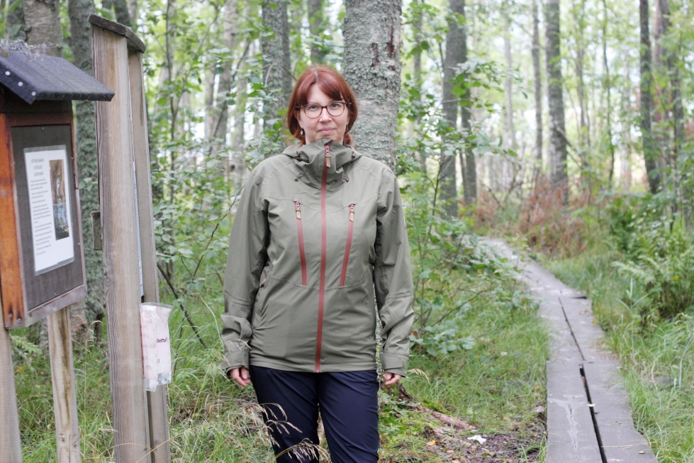 Asemanhoitaja Johanna Lakka luonnonsuojelualueen pitkospuilla. Lintuasema sijaitsee hieman hänen takanaan vasemmalla.