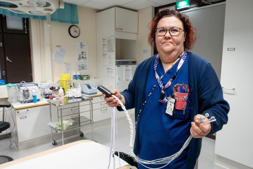 Sairaanhoitaja Susanna Oinonen on työskennellyt Tuupovaarassa 18 vuotta, josta suurimman osan terveysaseman vastaanotossa. Käsissään hänellä on Holter-laite, joka rekisteröi sydämen toimintaa esimerkiksi vuorokauden ajalta.  