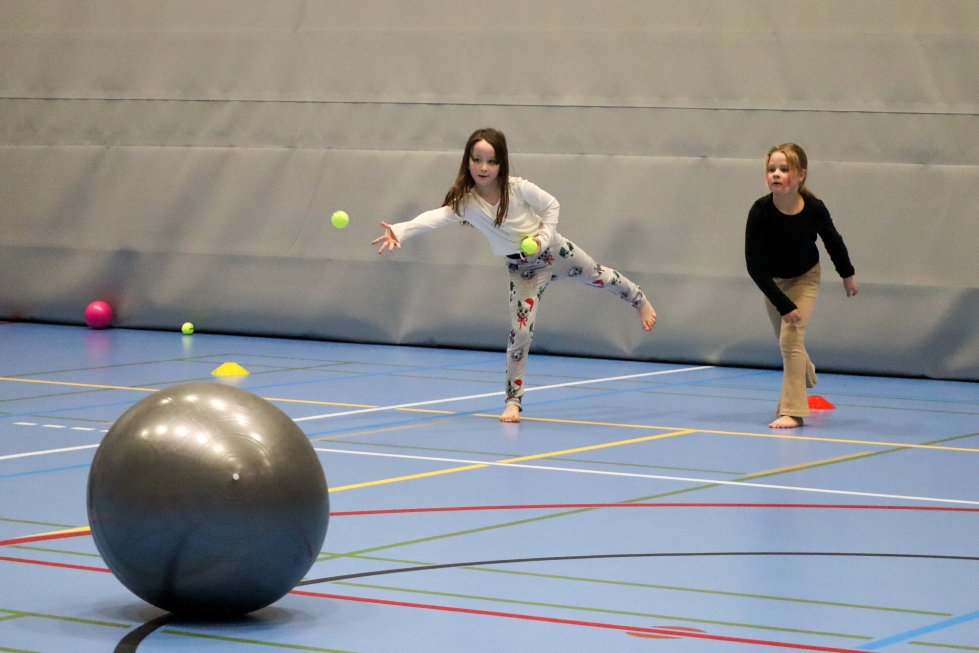 Lehmon koulun ekaluokkalaiset Hertta Haataja (vas.) ja Silja Karhu pelasivat vanhempien oppilaiden suunnittelemaa peliä, jossa jumppapalloa liikutettiin tennispalloja heittämällä toisen joukkueen alueelle.