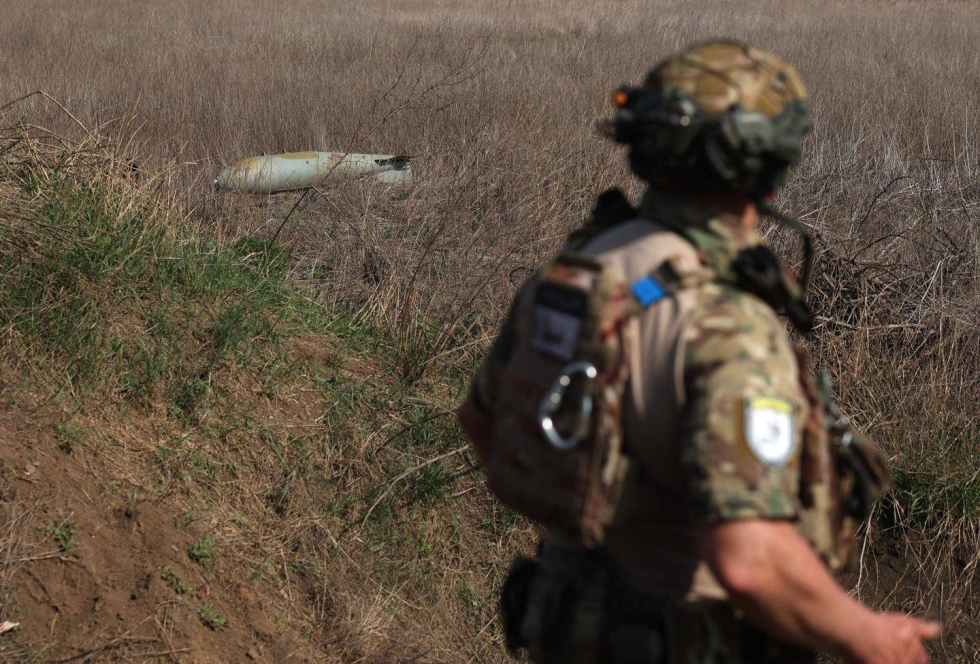 Ukrainalaissotilas kävelee suutariksi jääneen venäläispommin lähistöllä.