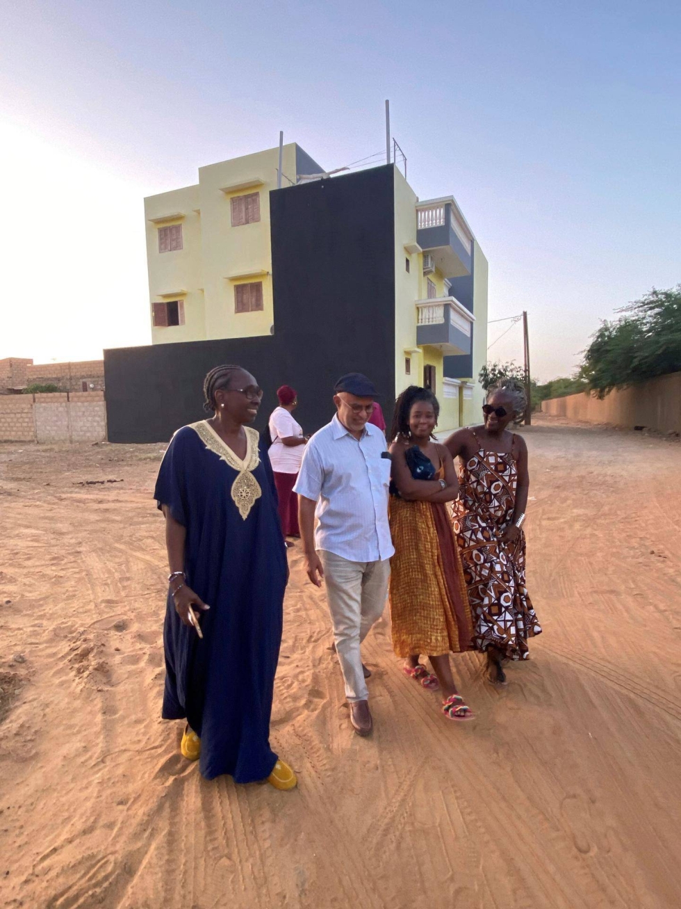 Mariame Racine Sow (edessä) ja perhettä Senegalin Podorissa. Takana näkyy perheen viime vuonna valmistunut talo, jonka rakentamista Sow rahoitti.
