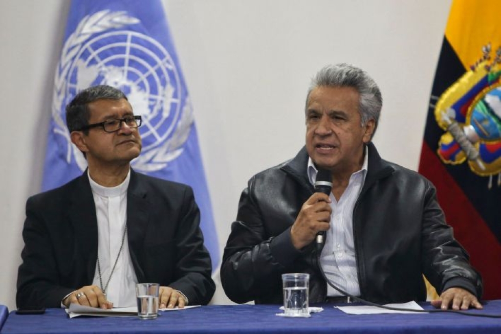 Ecuadorin presidentti Lenin Moreno (oik.) ja neuvotteluja välittävän kirkon arkkipiispa Luis Gerardo Cabrera neuvotteluissa alkuperäiskansojen johtajien kanssa. Lehtikuva/AFP