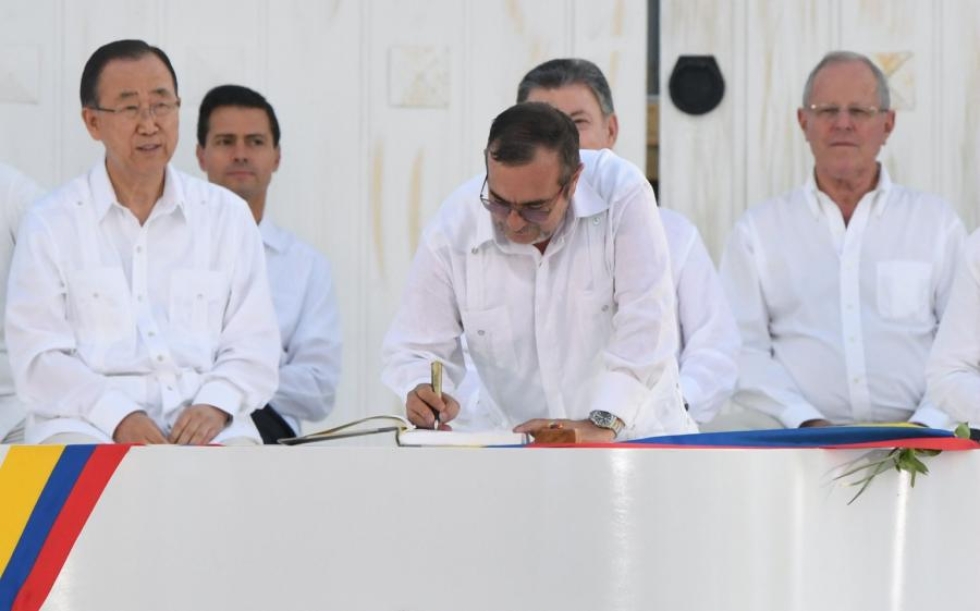 Farc-sissien johtaja Timoleon Jimenez allekirjoittamassa Kolumbian historiallista rauhansopimusta. Vasemmalla YK:n pääsihteeri Ban Ki-moon. LEHTIKUVA/AFP