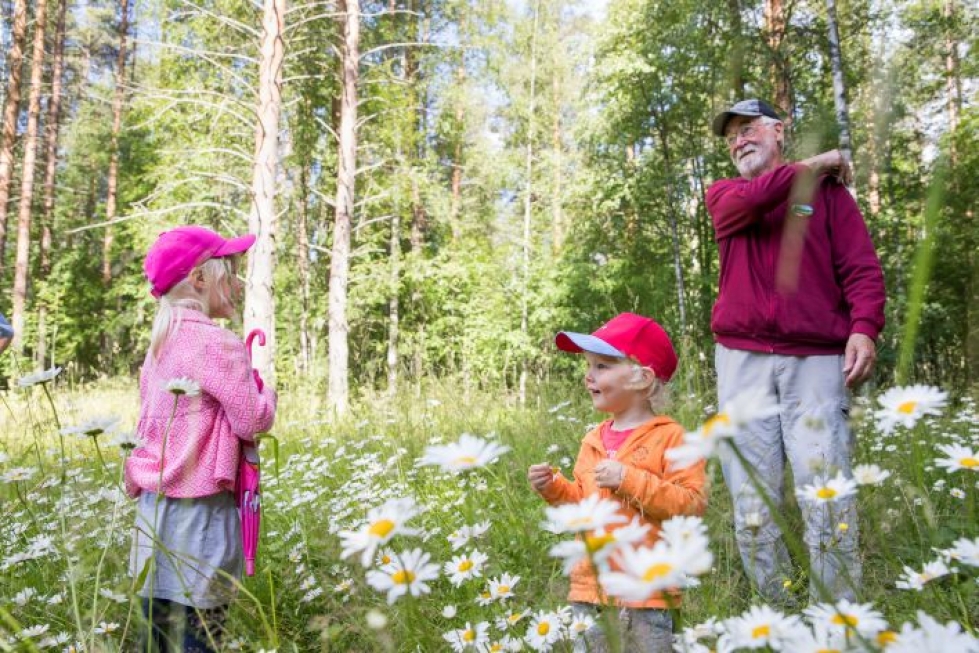 Viivi, 5, ja Panu Laatikainen, 2, sekä Juha Hämäläinen tutkimassa kukkia.