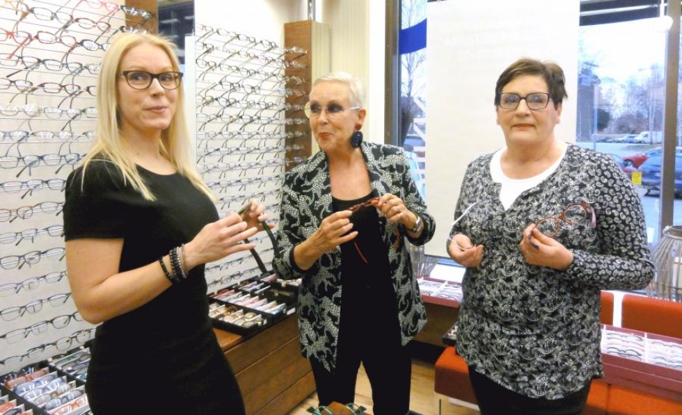 Anneli Akkila (oik.) on hankkimassa uusia silmälaseja. Yrittäjä Reetta Tolvanen (vas.) ja meikkitaiteilija Raili Hulkkonen hakevat vaihtoehtoja ja auttavat sovittamisessa.