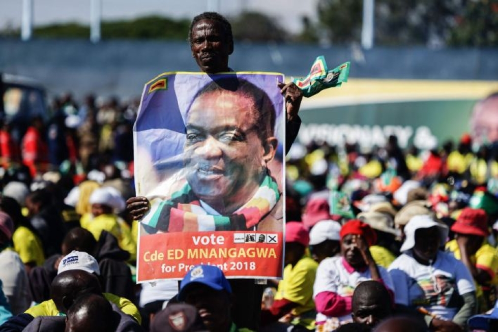 Mies pitelee kuvaa Zimbabwen presidentistä 23. kesäkuuta. LEHTIKUVA / AFP