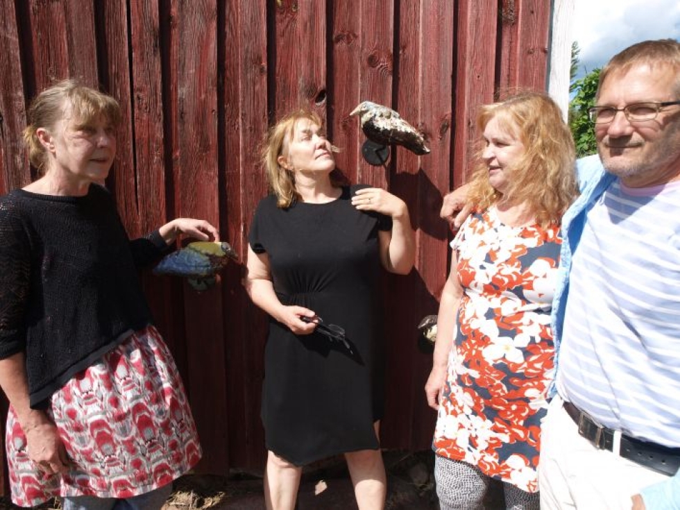 Tiina Salmi (vas.), Satu Loukkola, Merja Kupiainen ja Ahti Pitkänen ihmettelevät Johanna Turusen keraamisia lintuja, jotka ovat lennähtäneet piharakennuksen seinälle.