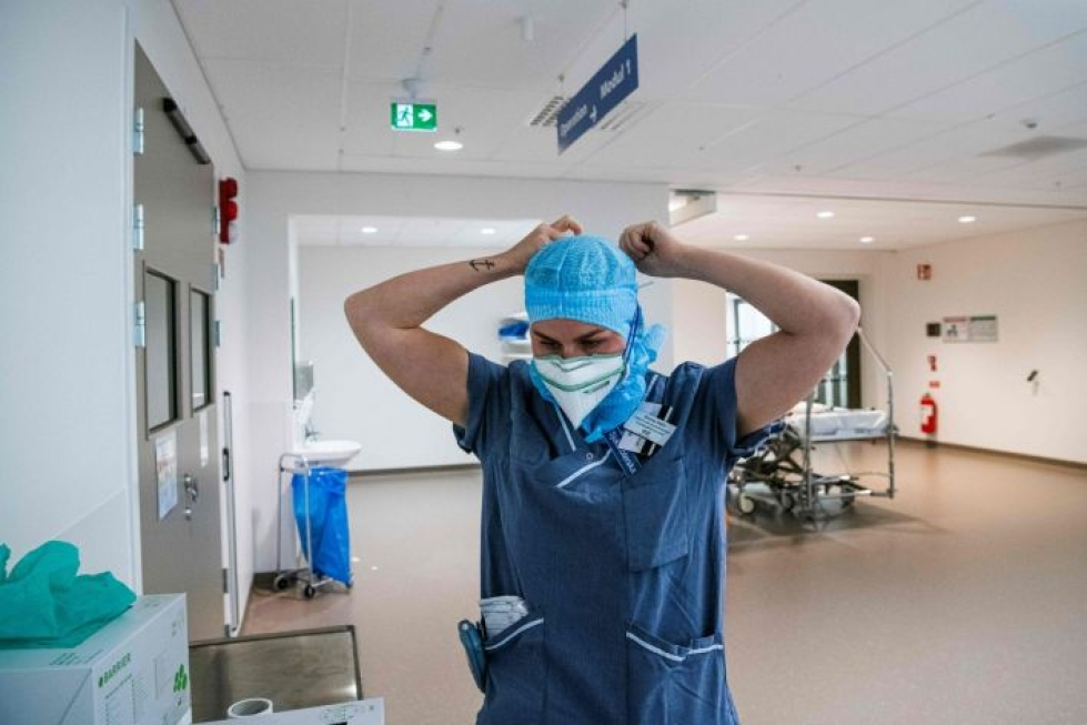Terveydenhuollon työntekijä sonnustautumassa suojavarusteisiin tukholmalaisen Södersjukhusetin teho-osastolla kesäkuussa. LEHTIKUVA / AFP