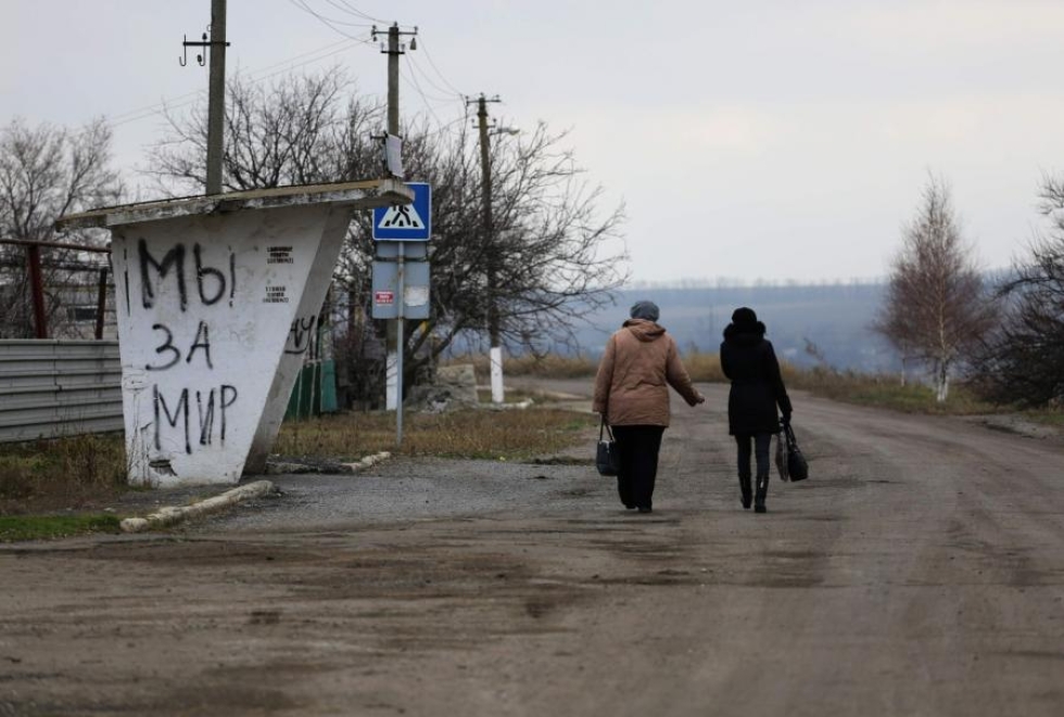 Asukkaita Pavlopolin kylässä Donetskin alueella. Bussipysäkissä lukee "olemme rauhan kannalla". LEHTIKUVA/AFP