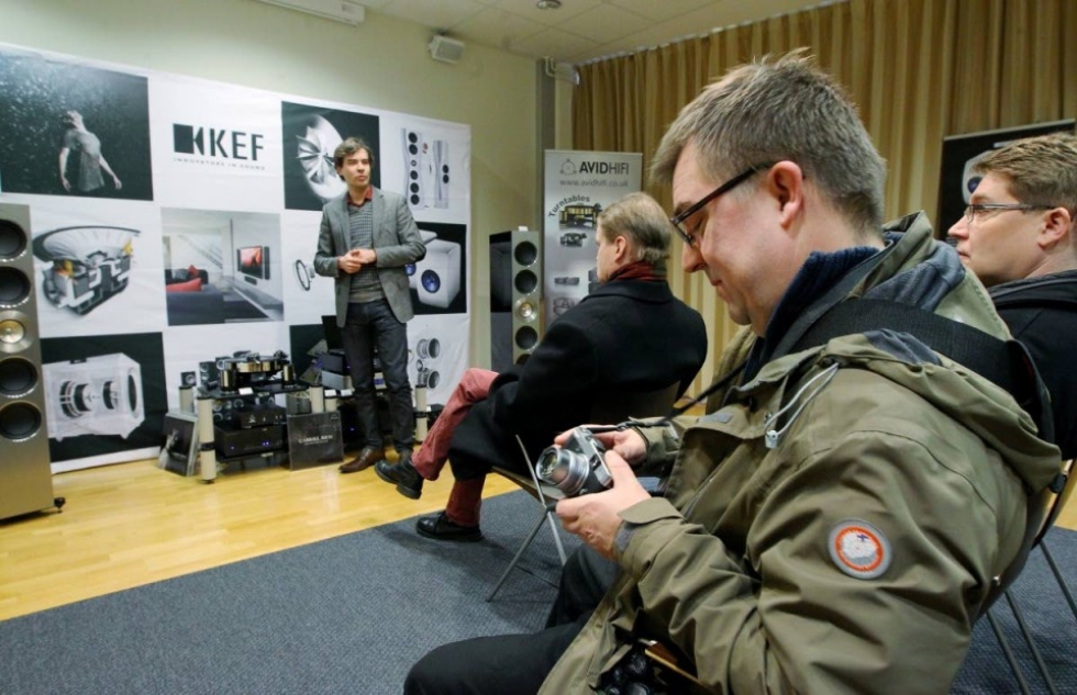 Markku Tomson esittelee KEF Reference -kaiuttimia. Sami Niemeläinen (edessä) virittelee kameraansa.