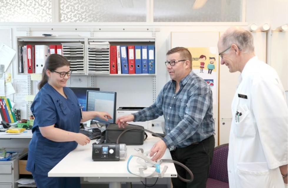 Unitutkimuksia tekevä sairaanhoitaja Minna Tanskanen ja keuhkosairauksien ylilääkäri Ilkka Salmi tarkastelevat Juha Pirisen CPAP-laitetta.