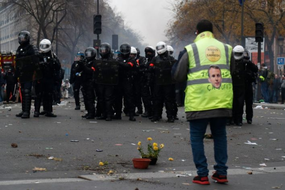 Keltaliivinen mielenosoittaja ja mellakkapoliiseja Pariisissa tänään. LEHTIKUVA/AFP