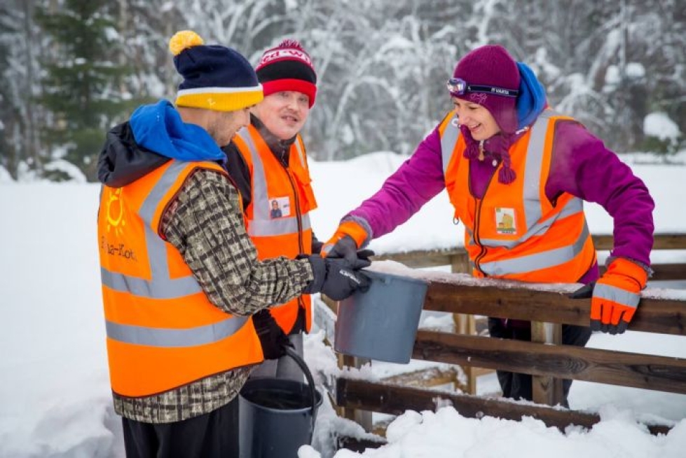 Tuomo Kurri (vasemmalla) ja Jere Hirvonen auttavat hoitokodin yrittäjää Outi Perälää kantamaan vettä lähteestä.