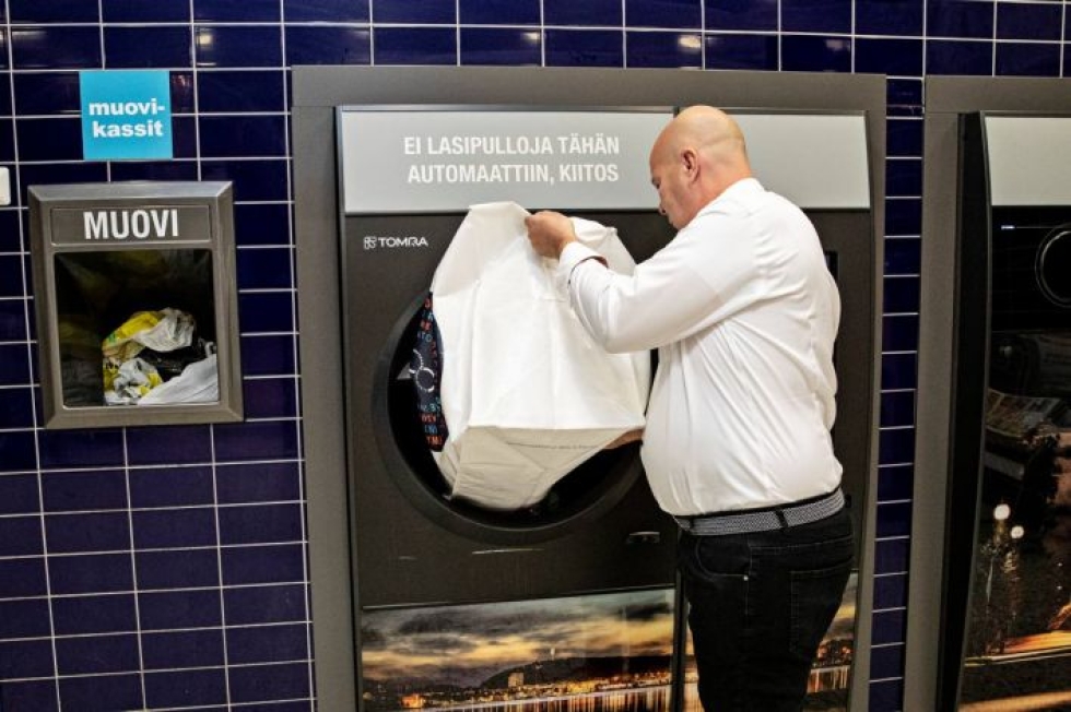 Päivärannan K-Citymarketin kauppias Pasi Toppari näyttää, miten uuteen automaattiin voi kipata kerrallaan säkillisen tölkkejä ja muovipulloja.