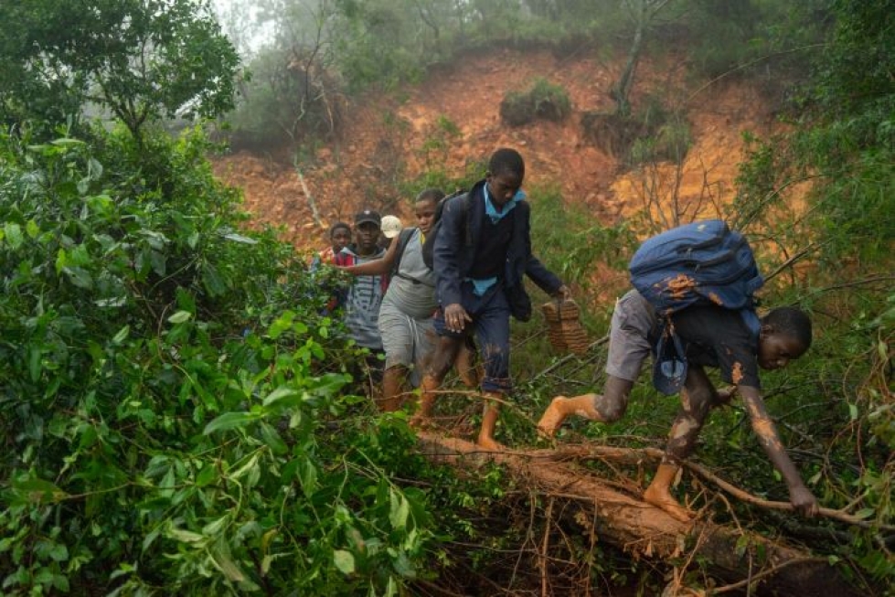 Koululaiset kävelivät myrskyn aiheuttaman mutavyöryn ohi sunnuntaina Mosambikissa. LEHTIKUVA/AFP