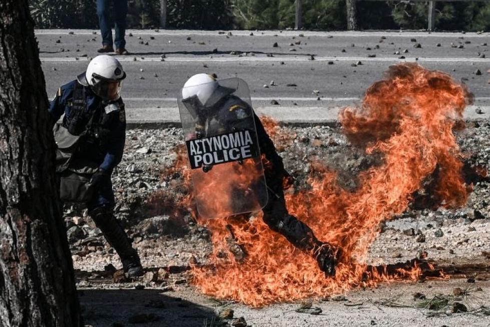 Mellakkapoliisi pyrkii pois liekeistä yhteenotoissa mielenosoittajien kanssa Mantamadosin kaupungin lähellä Kreikassa Lesboksen saarella. LEHTIKUVA/AFP