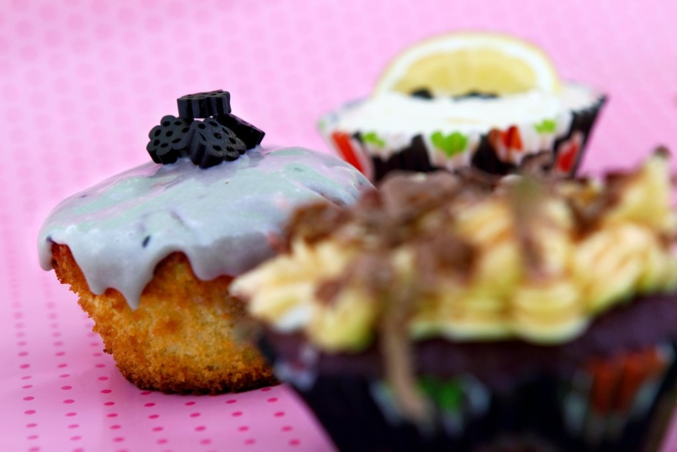 Kuppikakkuja kolmella tapaa: edessä suklaa-cupcake maapähkinäkuorrutteella, taustalla salmiakki- ja sitruuna-cupcakesit.