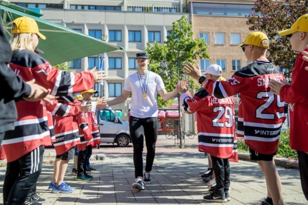Urho Vaakanainen saapui torijuhlaan juniorikiekkoilijoiden saattelemana. Kaulassa kiiltelevä kultamitali on vuodenvaihteen nuorten maailmanmestaruuskilpailuista.