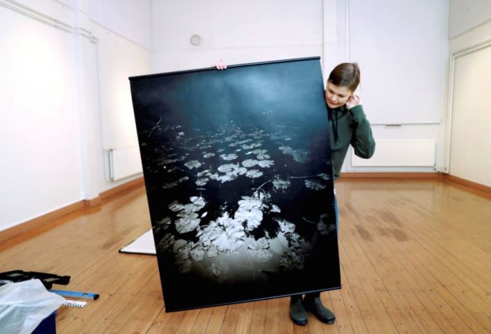 Kaisu Häkkänen ja yksi työ neulanreikäkameralla kuvattujen valokuvien sarjasta Metsän ääri.