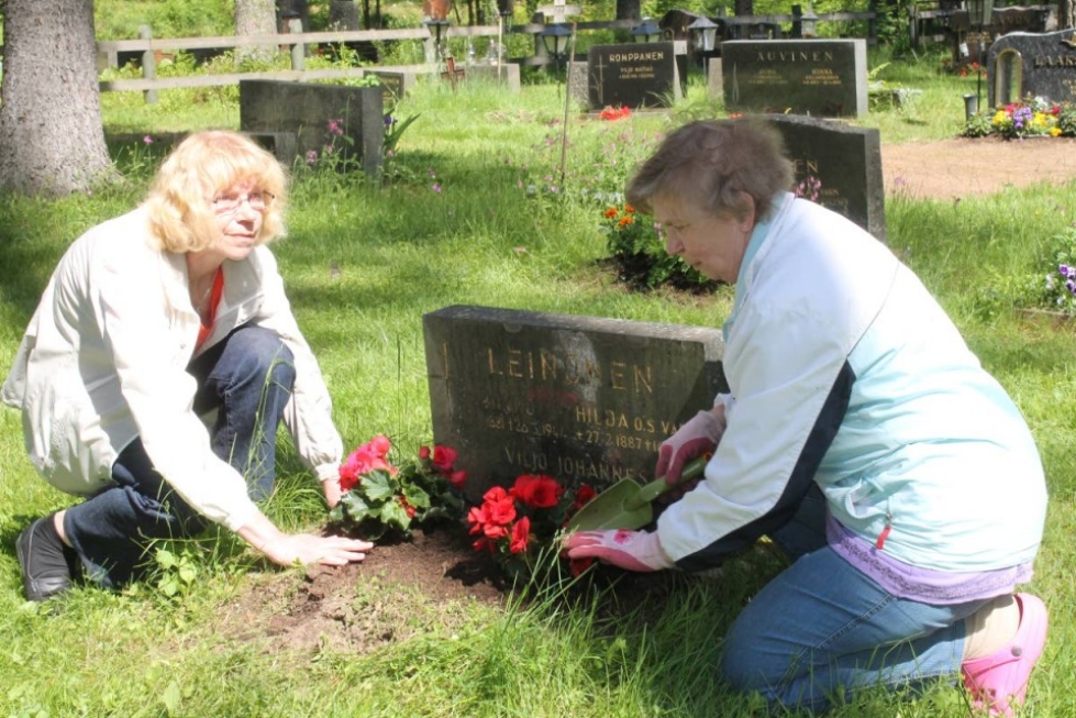 Raija Suokas (vas.) ja Pirkko Männistö istuttavat kukkia omaisensa haudalle Ilomantsissa.