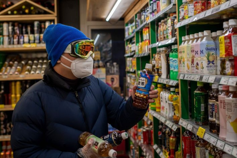 Kasvosuojaimella, käsineillä ja suojalaseilla koronavirukselta suojautunut mies teki ostoksia Pekingissä torstaina. LEHTIKUVA/AFP.