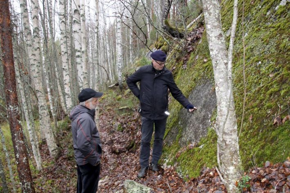 Tapio Tiensuu (vas.) ja Jari Lampinen tutkimassa kallioseinämässä olevaa tilojen rajamerkkiä.