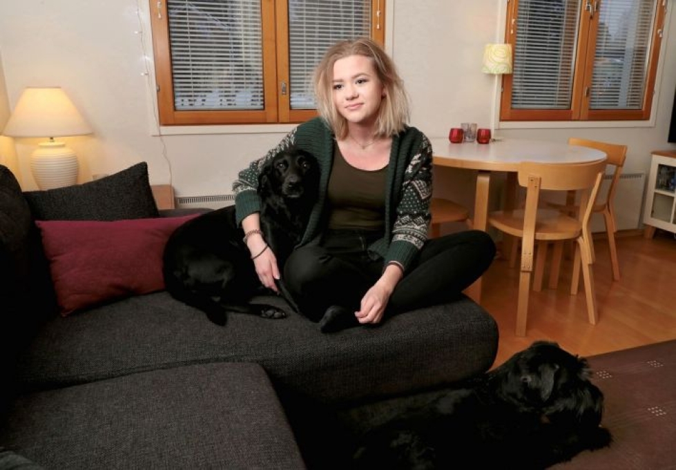 Ylämyllyläinen Anna Talkkari saa tänään valkolakkinsa. Kuvassa hänellä on kainalossaan Sylvi-koira, lattialla pötköttää Otto.