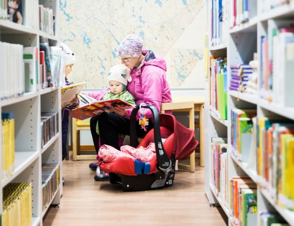 Minna Piipponen uppoutui tyttäriensä Miran, Katin ja Annin kanssa kirja-aarteiden pariin Tuupovaaran uudessa kirjastossa.