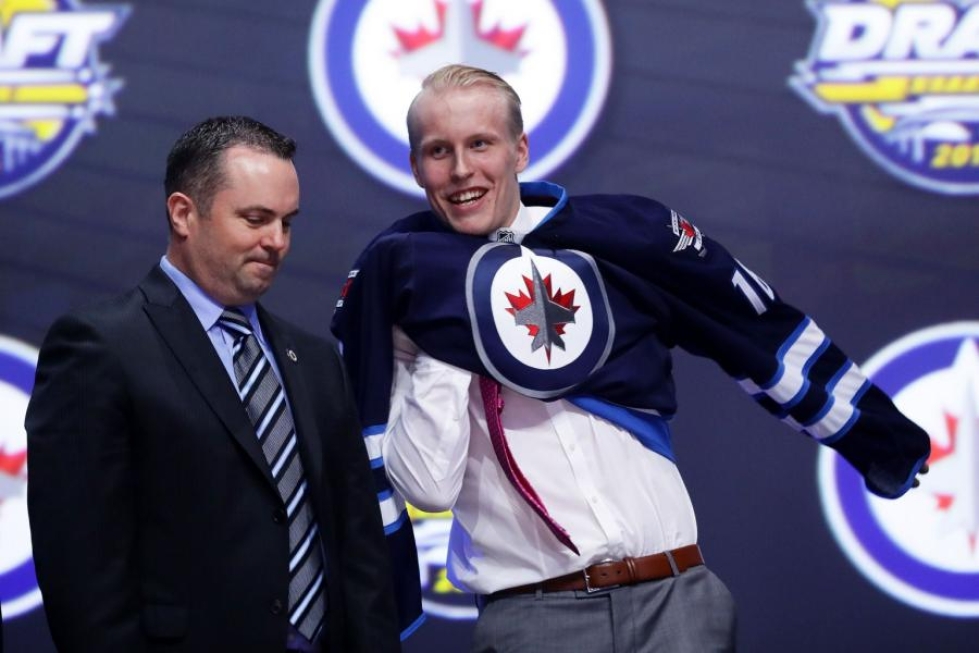 Patrik Laine puki Winnipegin pelipaidan päällensä NHL:n varaustilaisuudessa Buffalossa. LEHTIKUVA/AFP