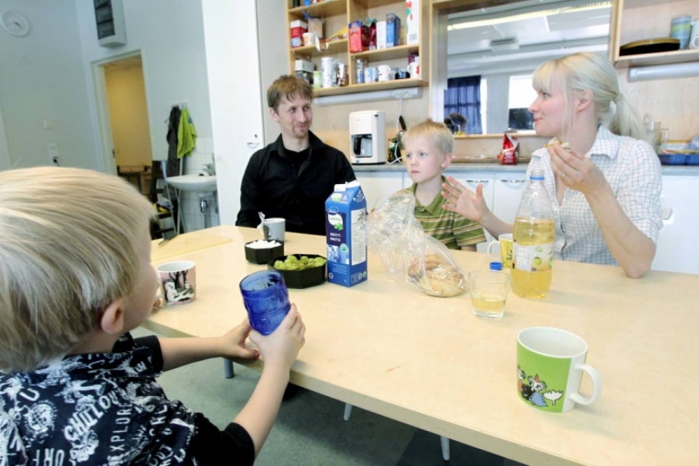 Vanhemmat Antti Timonen ja Tuula Halttunen yhdessä poikiensa Aapon ja Vernerin kanssa väliaikaisen kotinsa ruokapöydän ääressä. Vanhalla kansakoululla työ ja muu elämä lomittuvat sujuvasti.